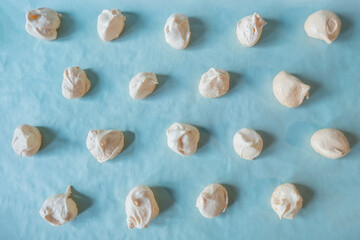 Homemade french milk-colored meringues on blue paper