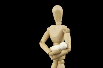Parenthood and love concept. Wooden mannequin holding small baby figure isolated on black...