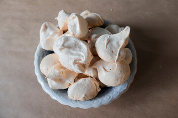 Homemade french milk-colored meringues on crumpled craft paper