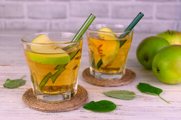 Two glasses of apple juice with a sprig of rosemary. Close-up.	