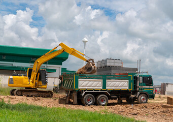 Excavator load soil to truck in construction site.