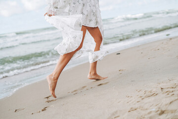 Fototapeta na wymiar Crop photo of Young beautiful woman in white dress enjoying life on the sea beach