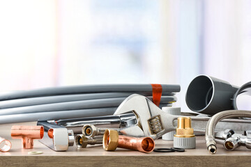 Material for plumbing works on wooden table and window background