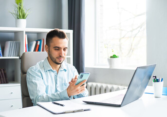 Young Man Works while Sitting in front of a Computer at Home. The Workplace of a Professional Worker, Freelancer or Student. Distance Work and Education Concept.