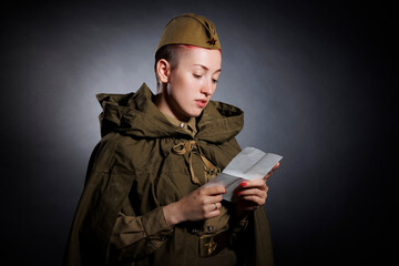 A young woman in a retro-style military uniform reads a paper letter.