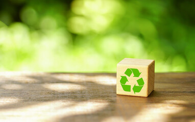 Wooden cube with recycle icon and green industrial on nature background and sunlight. Eco-friendly...