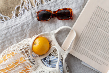 leisure and summer holidays concept - bag of oranges, sunglasses and magazine on blanket on beach...