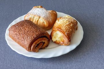 three sweet buns on a plate on a tablecloth