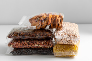 food storage, healthy eating and diet concept - close up of bags with dried fruits, cereals and nuts on white background