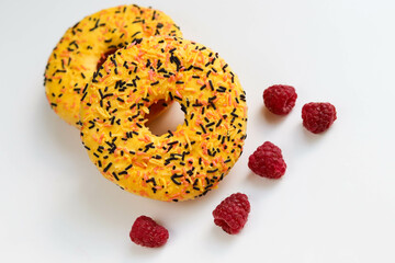sweet dessert. round donuts with yellow icing isolated on white background and raspberries