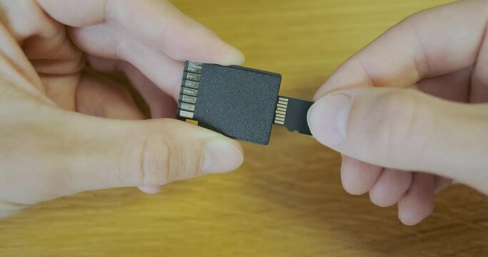 Insert micro sd memory card into sd adapter. Close-up, male hands insert a small memory card into the adapter.