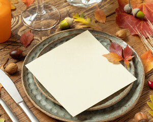 Autumn rustic  table setting with red, yellow and orange leaves, berries and blank card close up, mockup