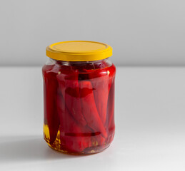 food, storage and preserve concept - close up of jar with pickled red hot chili peppers on table