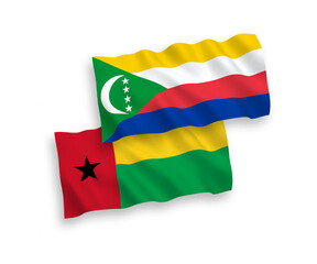 National vector fabric wave flags of Union of the Comoros and Republic of Guinea Bissau isolated on white background. 1 to 2 proportion.