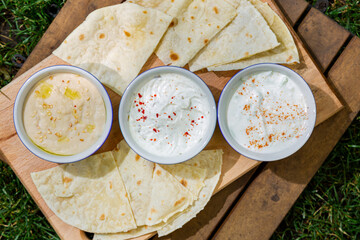 Pieces of pita bread with three different sauces