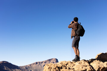 Naklejka premium Young man taking pictures on a road trip. Man making memories on the mountain.