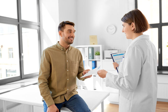 medicine, healthcare and people concept - female doctor giving prescription to man patient at hospital