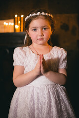 Little armenian redhead girl in ancient armenian monastery praying and looking at camera in front of candles