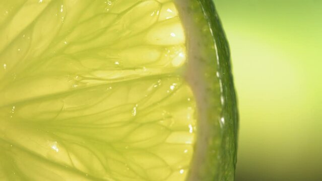 Drop of water flows down the surface of a ripe juicy Lime slice. Slow Motion 4K