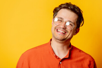 Stylish guy in eyeglasses on yellow background