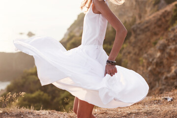 View of a girl in a fluttering white dress in the wind. Girl with long slender legs is dancing on...