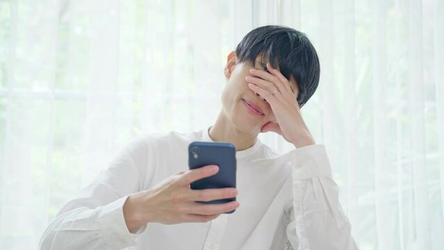 スマホを見ながら悩む男性