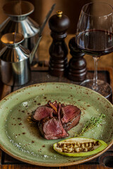 Medium rare veal rack with a glass of red wine.