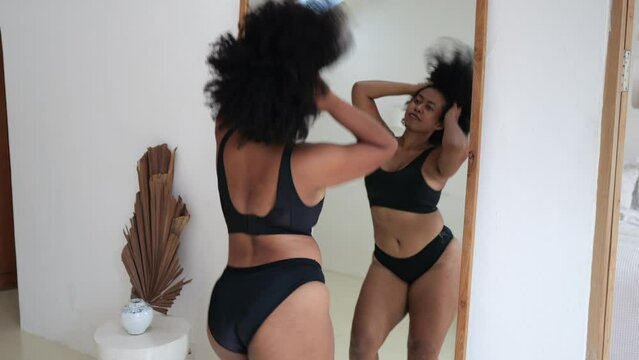 A fat woman in underwear is body-positive. A dark-skinned, plus-size woman model dances at home, does not pay attention to her excess mass, loves herself for who she is. Afro-american in the apartment