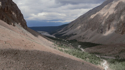 Mountains of Aktru valley with river and forest under white clouds in Altai