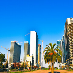 Batumi, Georgia- 17th november, 2021: Static time lapse Batumi city panorama with cars in traffic and real estate construction site with cranes in sunny day. Construction work real estate development 