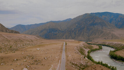 Mountains valley of Altai with traffic cars on Chuya highway under dramatic sky