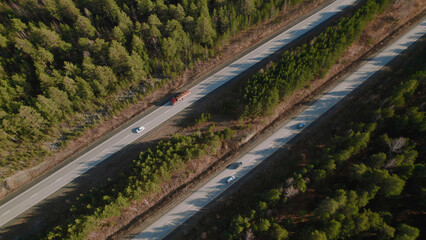 Highway road with traffic cars between green forest