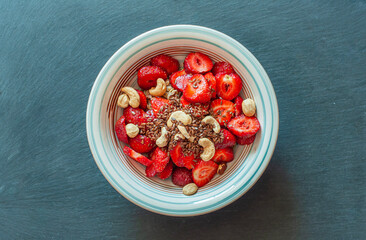 Plate with breakfast, dessert made from strawberries, nuts and flax seeds, healthy food, diet, proper nutrition, vegetarian recipes, space for text, top view, on a black background