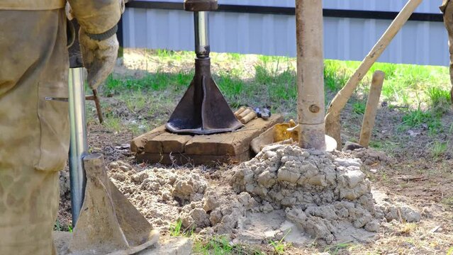 Team of workers with drilling rig on car are drilling artesian well for water in ground. Insertion of metal casing pipe into ground, installation of individual drinking supply, June 28, 2022, Russia, 