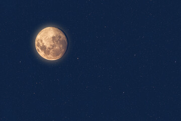 Naklejka na ściany i meble Full moon at dusk glowing against blue starry sky dark background