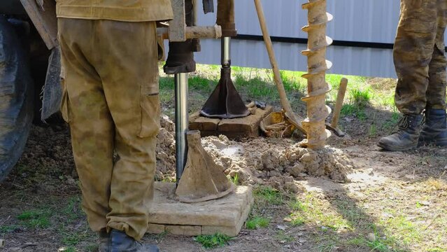 Team of workers with drilling rig on car are drilling artesian well for water in ground. Insertion of metal casing pipe into ground, installation of individual drinking supply, June 28, 2022, Russia, 