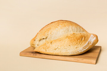 Freshly baked bread on cutting board against white wooden background. perspective view bread with copy space