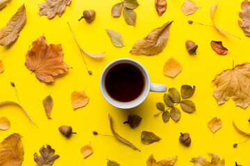 Fototapeta na wymiar Flat lay composition with colorful Autumn cup of coffee and leaves on a color background. top view