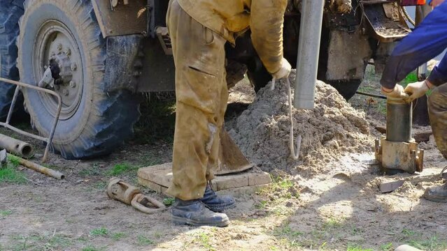 Team of workers with drilling rig on car are drilling artesian well for water in ground. Insertion of metal casing pipe into ground, installation of individual drinking supply, June 28, 2022, Russia, 