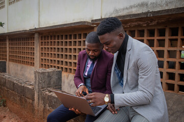 Two colleagues working an a project together look at a laptop screen, synergy and work together...