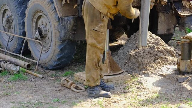 Team of workers with drilling rig on car are drilling artesian well for water in ground. Insertion of metal casing pipe into ground, installation of individual drinking supply, June 28, 2022, Russia, 
