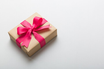 Wrapped christmas or other holiday handmade present in craft paper with colored ribbon. Present box, decoration of gift on table, top view with copy space