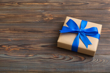 Wrapped christmas or other holiday handmade present in craft paper with colored ribbon. Present box, decoration of gift on table, top view with copy space