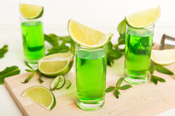 Sweet refreshing mint liqueur, with ice and mint leaves on table background, Shots with lime slice and mint flat lay