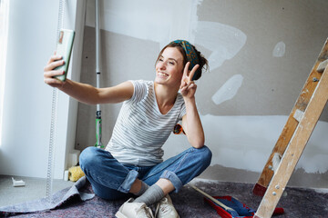 Young woman renovating her apartment and taking a selfie with cell phone