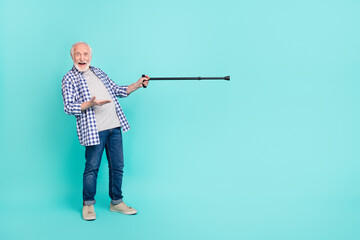 Full size photo of positive cheerful grandpa indicate stick empty space isolated on teal color background