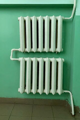 Old-fashioned cast iron water radiator with pipes in hallway or living room in soviet union style. Heating building home of winter. Vertical shot. - 514173744