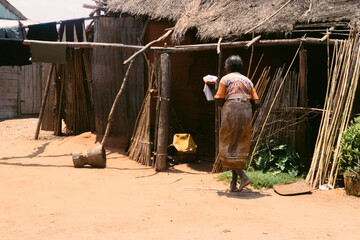 Older woman carrying laundry in a typical wooden village in the desert area of Madagascar. © Beatriz