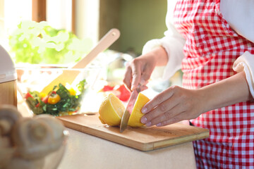 Obraz na płótnie Canvas Woman cutting fresh lemon at countertop in kitchen, closeup