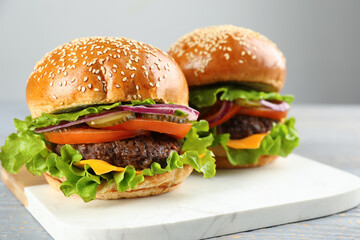 Tasty burgers on white marble board, closeup. Fast food